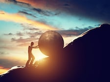 Man rolling huge concrete ball up hill.